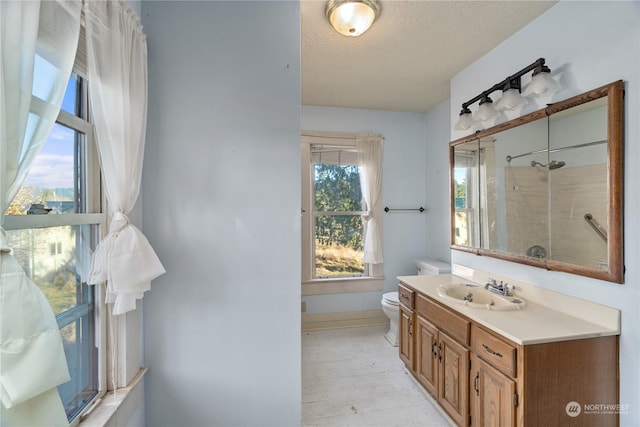 bathroom featuring a tile shower, vanity, a textured ceiling, wood-type flooring, and toilet