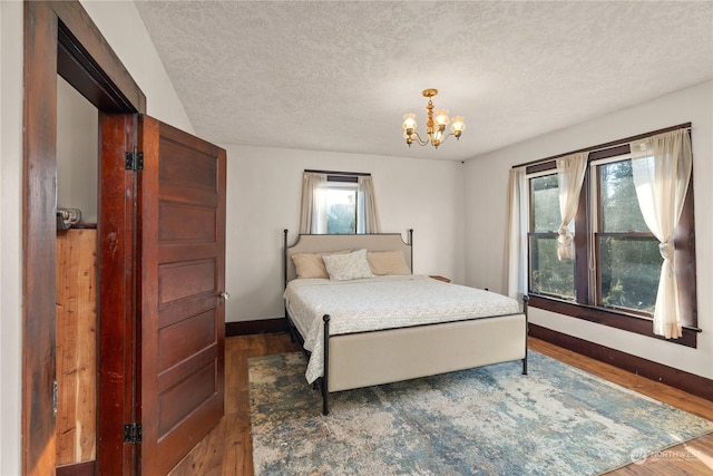 bedroom featuring a textured ceiling, dark hardwood / wood-style floors, and a notable chandelier