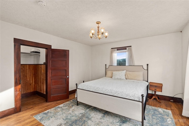 bedroom featuring wood-type flooring, a textured ceiling, and a notable chandelier