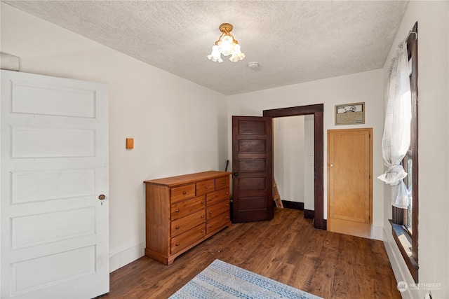 bedroom with a textured ceiling, dark hardwood / wood-style floors, and a notable chandelier