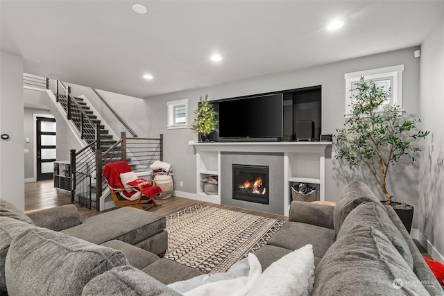 living room featuring a tiled fireplace and wood-type flooring