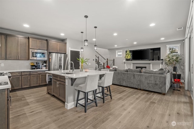 kitchen with backsplash, a kitchen island with sink, a wealth of natural light, appliances with stainless steel finishes, and a breakfast bar area