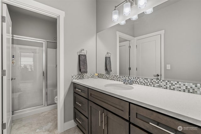 bathroom with vanity, toilet, an enclosed shower, and backsplash