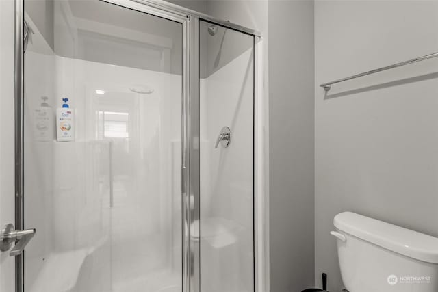 bathroom with toilet and a shower with shower door