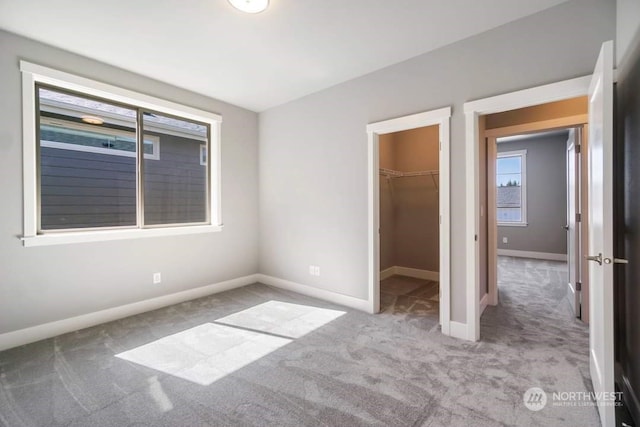 unfurnished bedroom featuring a walk in closet, a closet, and light colored carpet