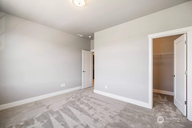 unfurnished bedroom with light carpet, a spacious closet, and a closet