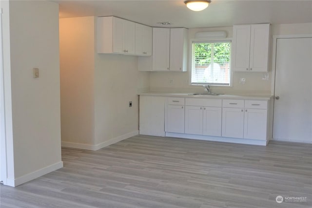 kitchen featuring light hardwood / wood-style floors, white cabinetry, and sink