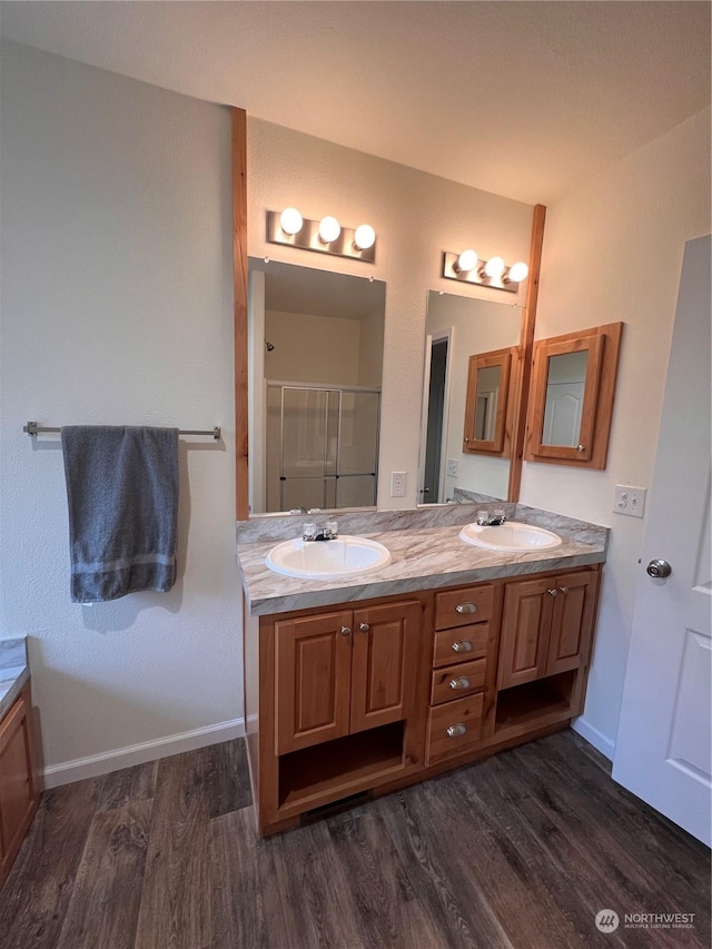 16818 57th St NW, Vaughn, WA 98394 - bathroom featuring wood finished floors, double vanity, and a shower stall
