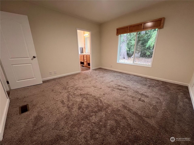 unfurnished bedroom with dark colored carpet and connected bathroom