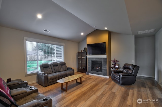 living room with a fireplace, wood-type flooring, and vaulted ceiling