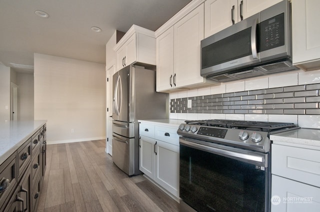 kitchen with dark hardwood / wood-style floors, backsplash, white cabinets, light stone counters, and stainless steel appliances