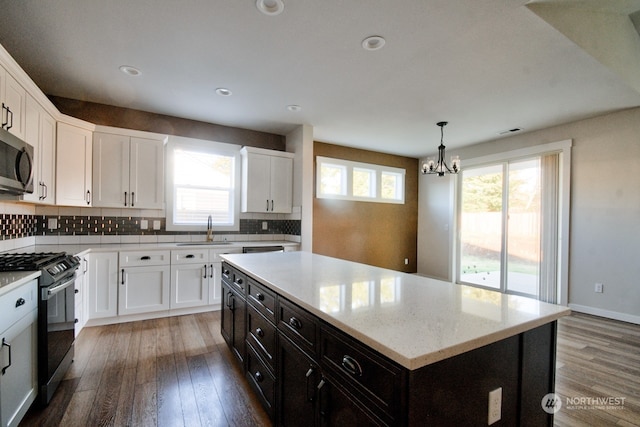 kitchen featuring sink, white cabinetry, stainless steel appliances, a center island, and decorative light fixtures