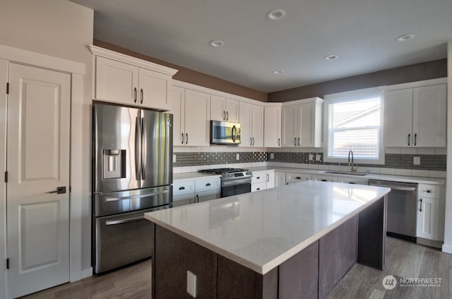 kitchen featuring sink, a center island, hardwood / wood-style flooring, stainless steel appliances, and white cabinets