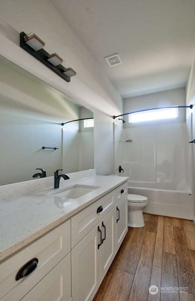 full bathroom featuring vanity, hardwood / wood-style flooring, bathing tub / shower combination, and toilet