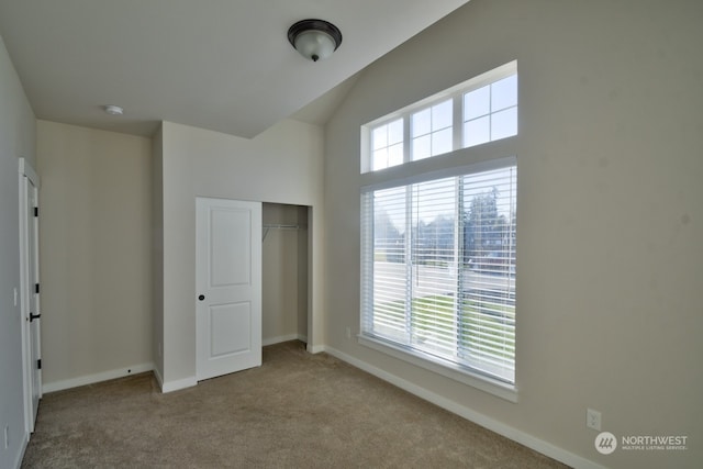 unfurnished bedroom featuring multiple windows, lofted ceiling, carpet floors, and a closet