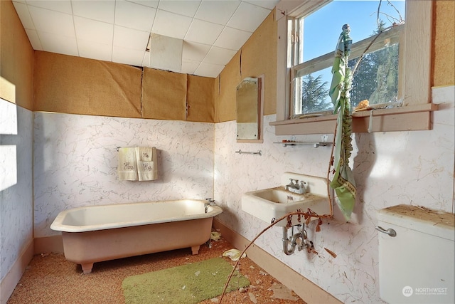 full bathroom with a freestanding bath, a sink, and wallpapered walls