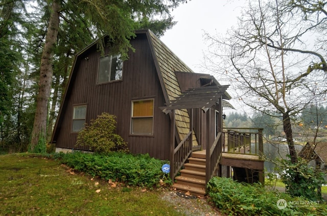 view of side of property featuring stairs, a gambrel roof, and a wooden deck