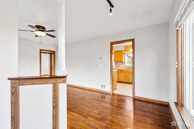 unfurnished living room featuring light wood-type flooring, ornate columns, and a healthy amount of sunlight