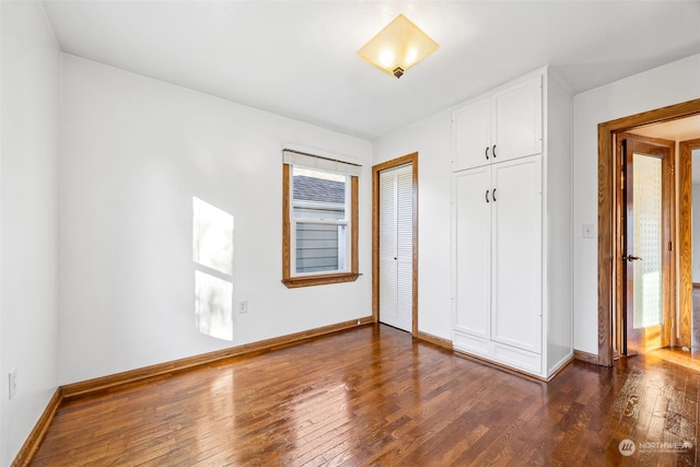 unfurnished bedroom featuring a closet, dark hardwood / wood-style flooring, and multiple windows