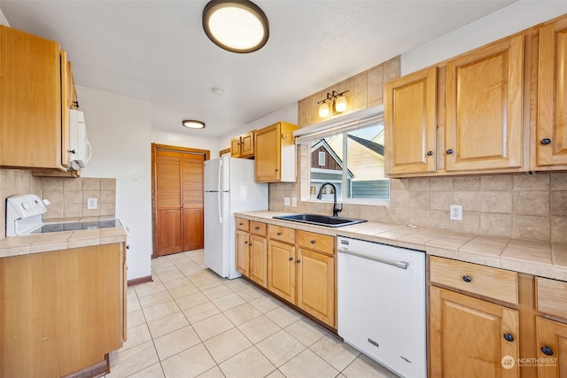 kitchen with backsplash, tile counters, sink, and white appliances