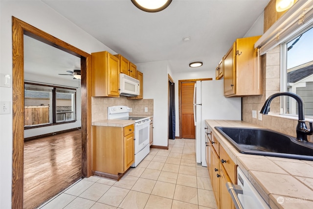 kitchen featuring ceiling fan, sink, tasteful backsplash, white appliances, and light tile patterned floors