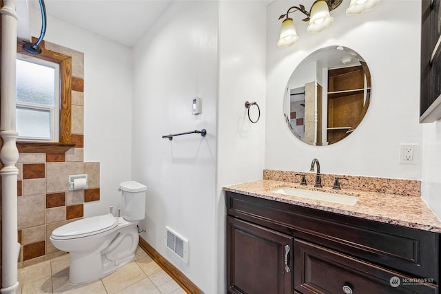 bathroom with tile patterned floors, vanity, toilet, and tile walls