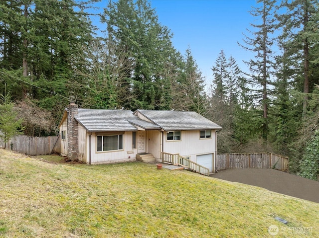 view of front of property with a garage, a chimney, a front yard, and fence