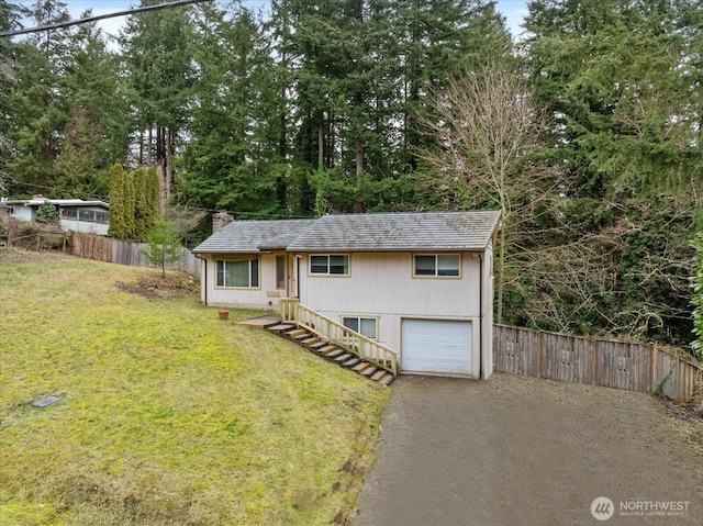 view of front of house with a garage, a chimney, a front lawn, and fence