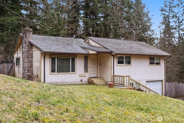 ranch-style house featuring a front lawn, an attached garage, fence, and a chimney