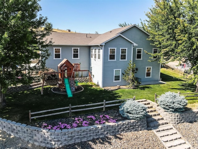 rear view of house featuring a playground and a lawn