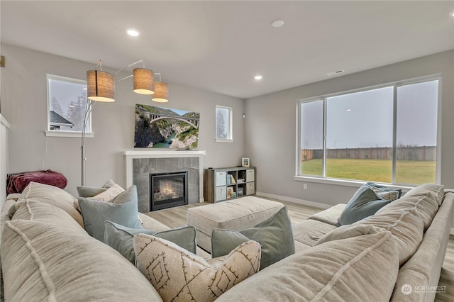 living room featuring light hardwood / wood-style floors and a tiled fireplace