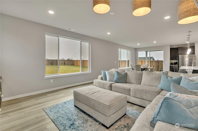 living room with light hardwood / wood-style flooring, plenty of natural light, and sink