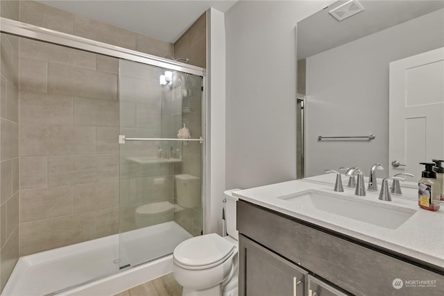 bathroom featuring vanity, hardwood / wood-style flooring, toilet, and a shower with door