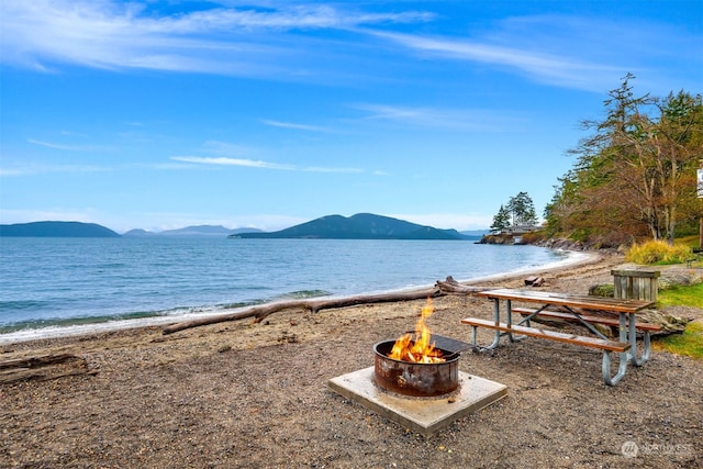 property view of water with an outdoor fire pit, a view of the beach, and a mountain view