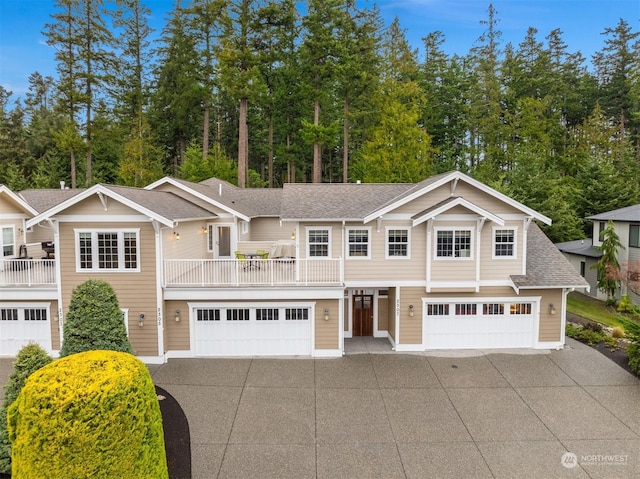 view of front facade featuring a shingled roof, concrete driveway, a balcony, and a garage