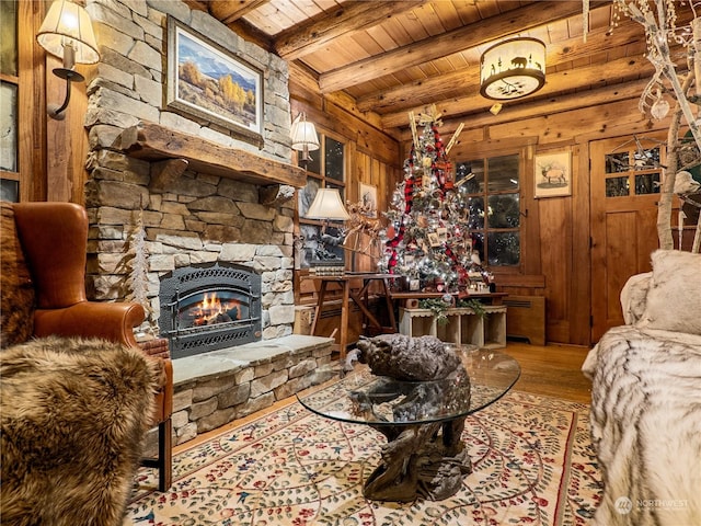 living room featuring beam ceiling, wooden ceiling, a fireplace, hardwood / wood-style floors, and wood walls