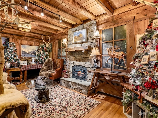 living area featuring beamed ceiling, wooden walls, light hardwood / wood-style floors, and wooden ceiling