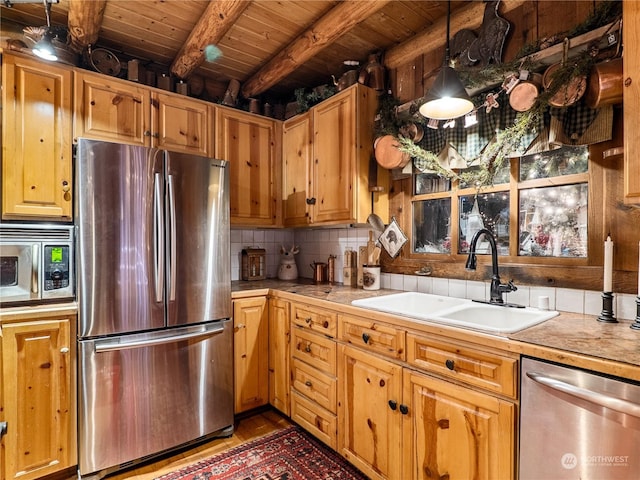 kitchen with sink, beamed ceiling, pendant lighting, wood ceiling, and appliances with stainless steel finishes