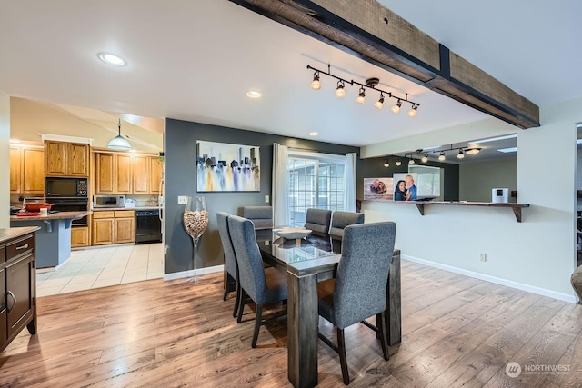 dining room featuring beam ceiling and light wood-type flooring