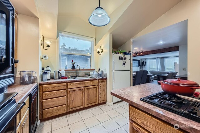 kitchen with black appliances, light tile patterned floors, sink, and vaulted ceiling