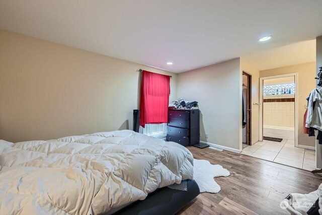 bedroom with ensuite bathroom and light wood-type flooring