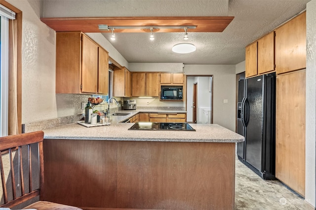 kitchen featuring track lighting, black appliances, sink, a textured ceiling, and kitchen peninsula