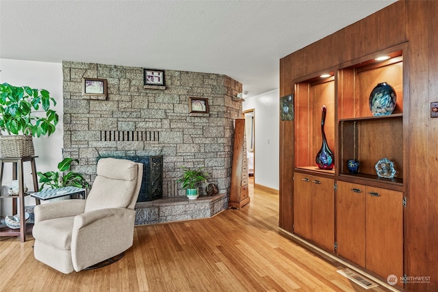 living area with a fireplace, a textured ceiling, and light hardwood / wood-style floors