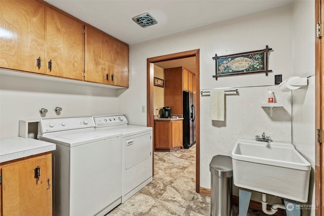 laundry area featuring cabinets, washing machine and dryer, and sink