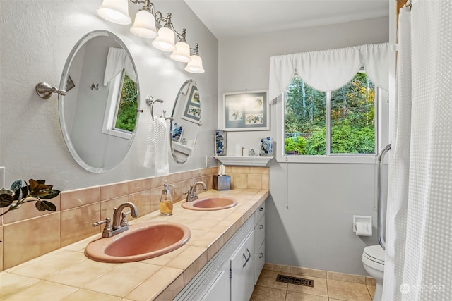 bathroom with tile patterned flooring, vanity, tasteful backsplash, and toilet