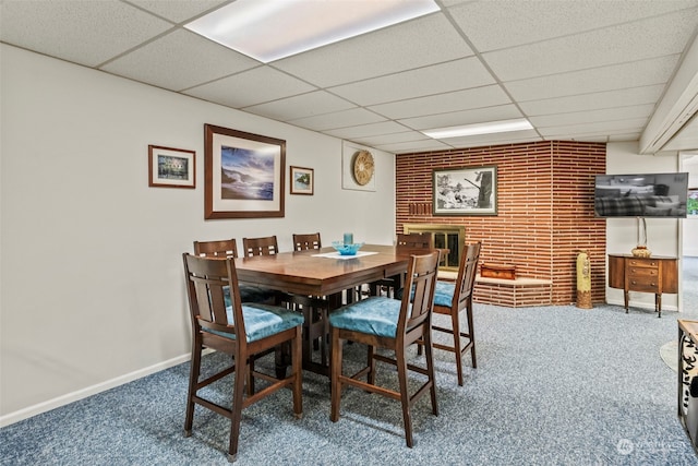 dining room featuring a paneled ceiling, carpet floors, and brick wall