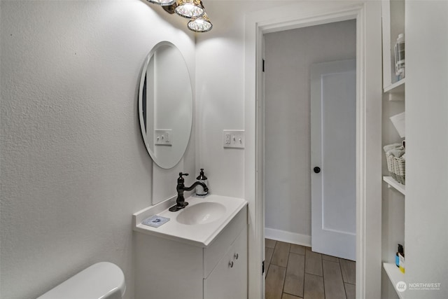 bathroom with wood-type flooring, vanity, and toilet