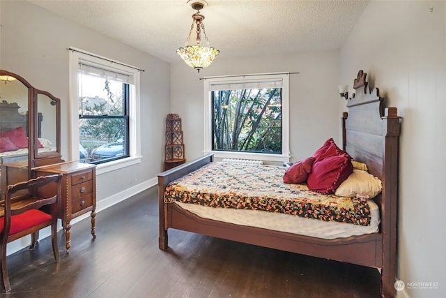 bedroom with multiple windows, dark wood-type flooring, and a textured ceiling