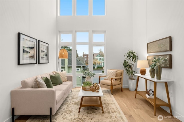 interior space with light wood finished floors, a high ceiling, and baseboards