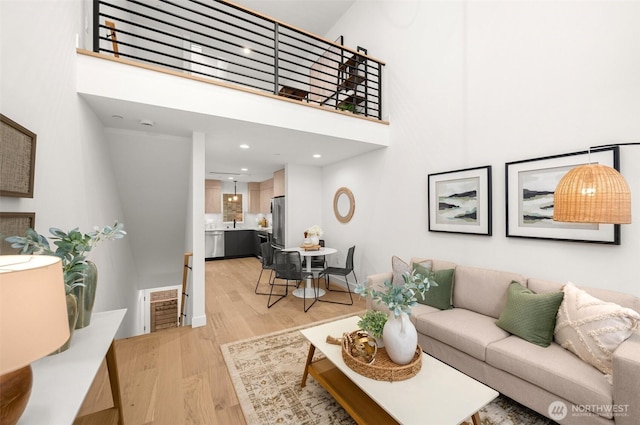 living room with a high ceiling, recessed lighting, visible vents, and light wood-type flooring